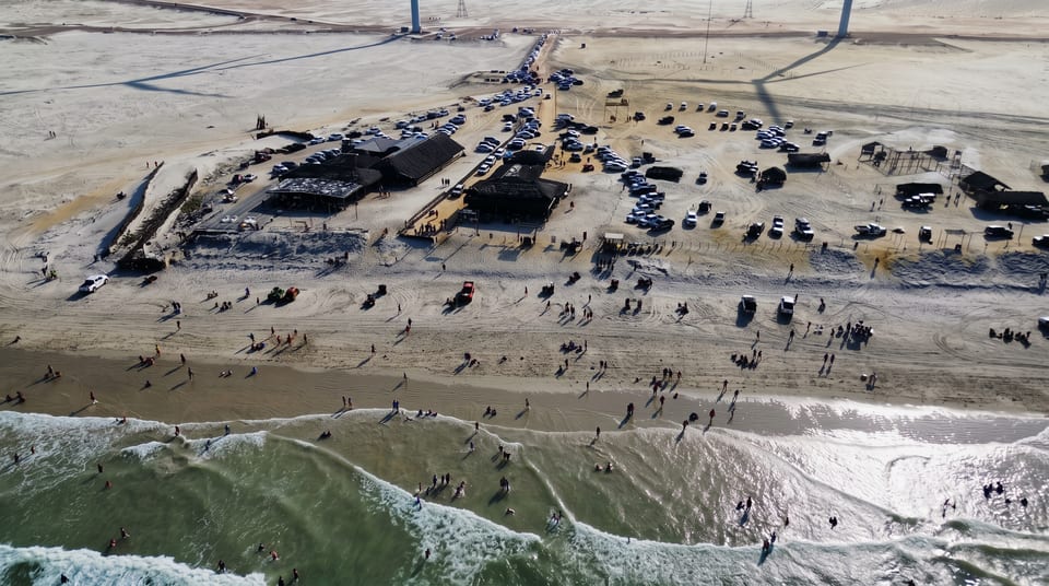 Vista aérea da praia em Paulino Neves, com ondas, areia e a orla movimentada