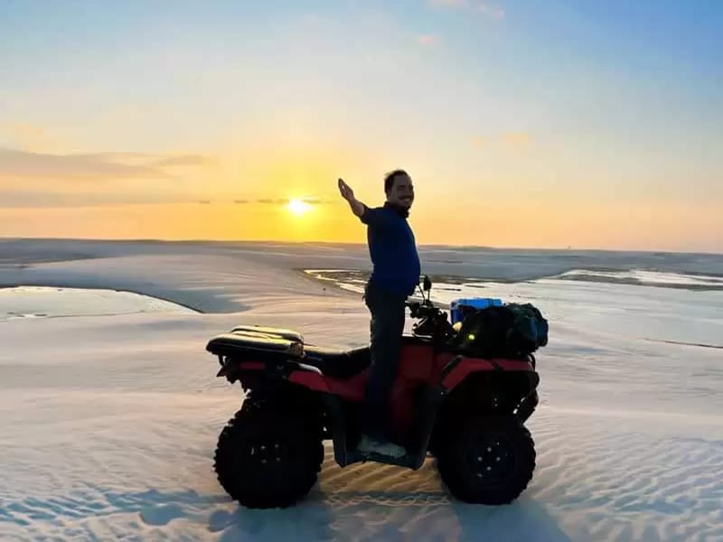 Piloto em quadriciclo durante o pôr do sol nas dunas